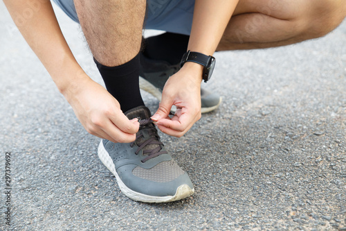 Man runner tying running shoes before run for exercise in the morning. Man runner checking shoe in order to get ready to run.
