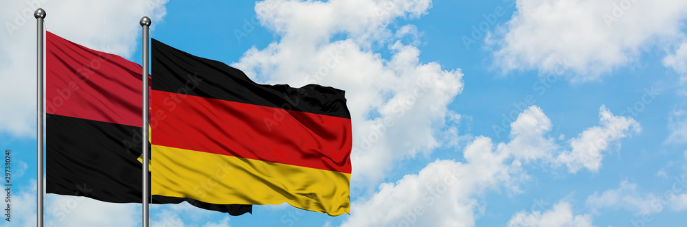 Angola and Germany flag in the wind against white cloudy blue sky together. Diplomacy international relations. Stock Photo | Adobe Stock