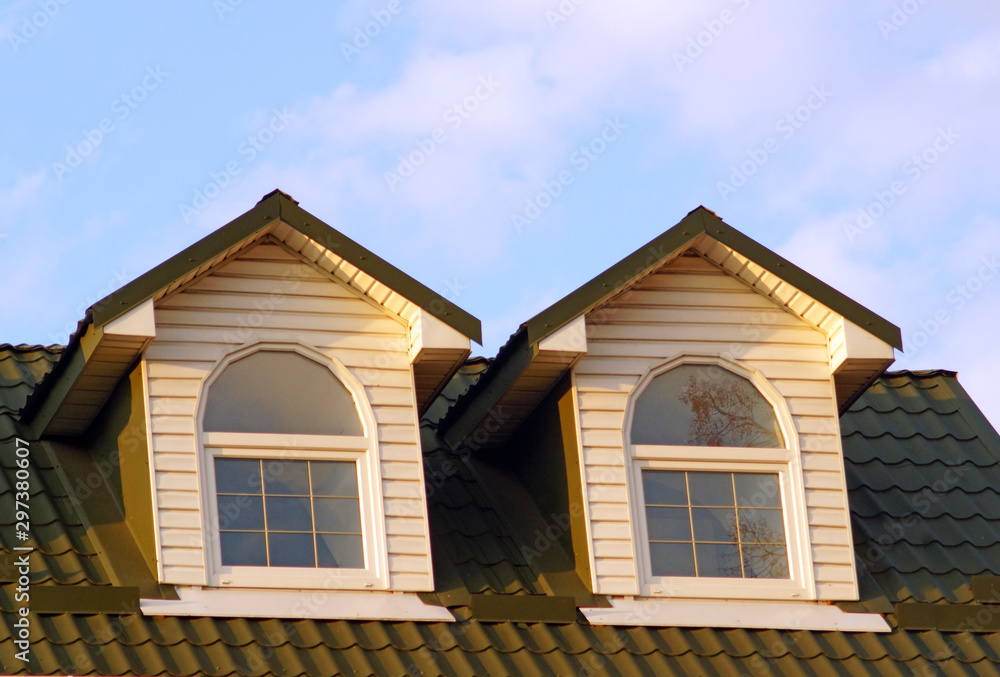 Two attic windows with white frames on the roof of red tiles
