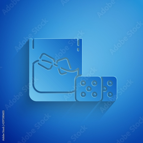 Paper cut Game dice and glass of whiskey with ice cubes icon isolated on blue background. Casino gambling. Paper art style. Vector Illustration