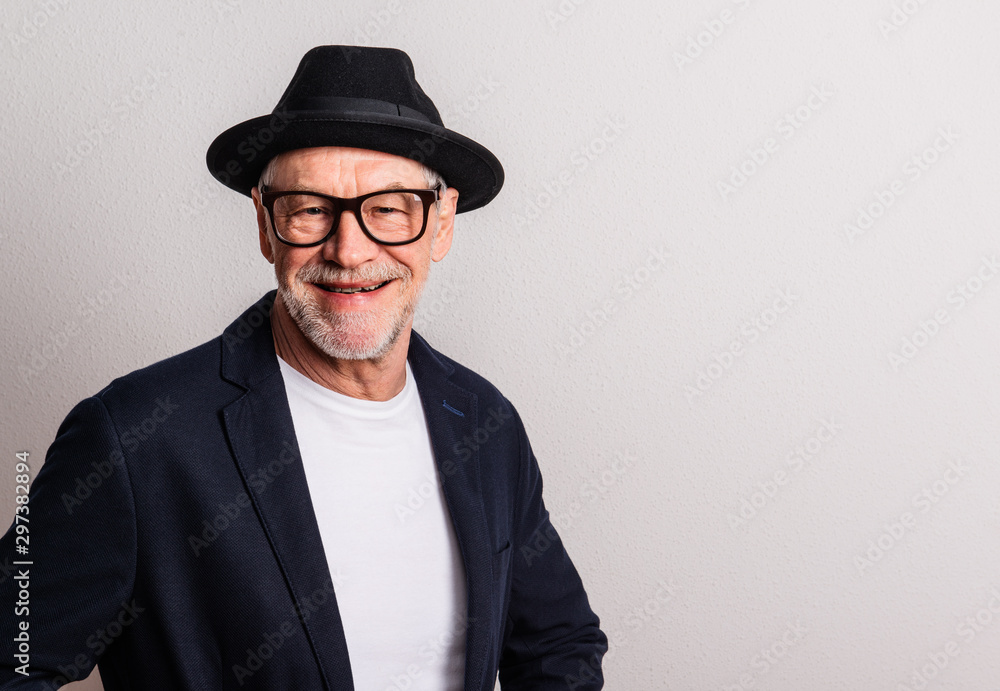 Portrait of a senior man with hat and glasses in a studio. Copy space. Portrait of a senior man with hat and glasses in a studio. Copy space.