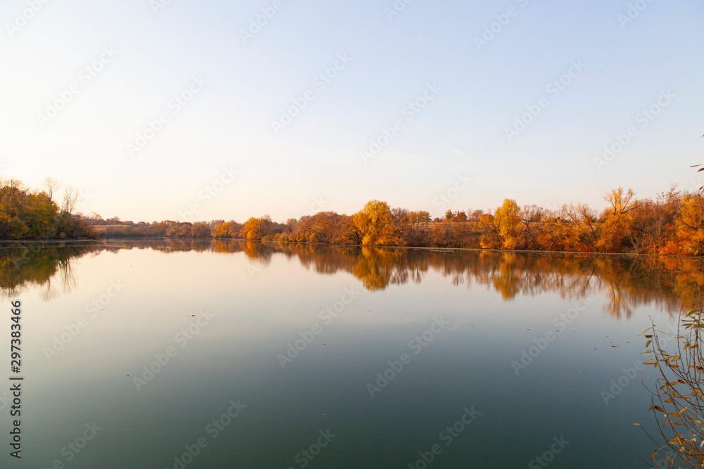 sunny autumn day with yellow trees. Lake with trees. Place under the text. Autumn forest at headquarters, lake, river.