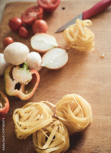 Italian cuisine background, with tomatoes, spaghetti, mushrooms, peppers, onions on a wooden brown board
