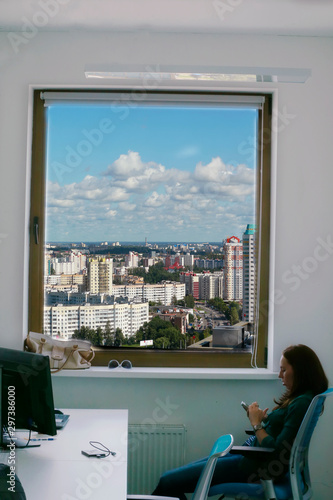 Silhouette of a woman in the office at work against the background of a window with a cityscape. Office work concept.. Work as a secretary in an office in a big city.