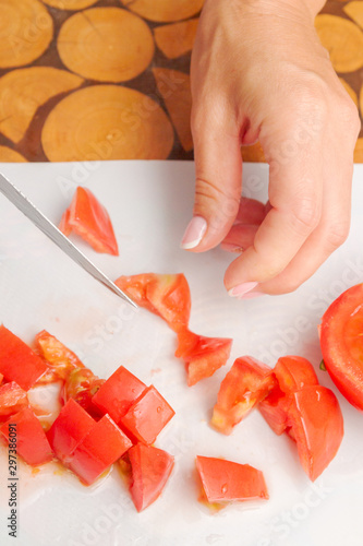 Dicing fresh ripe tomatoes on a white cutting Board
