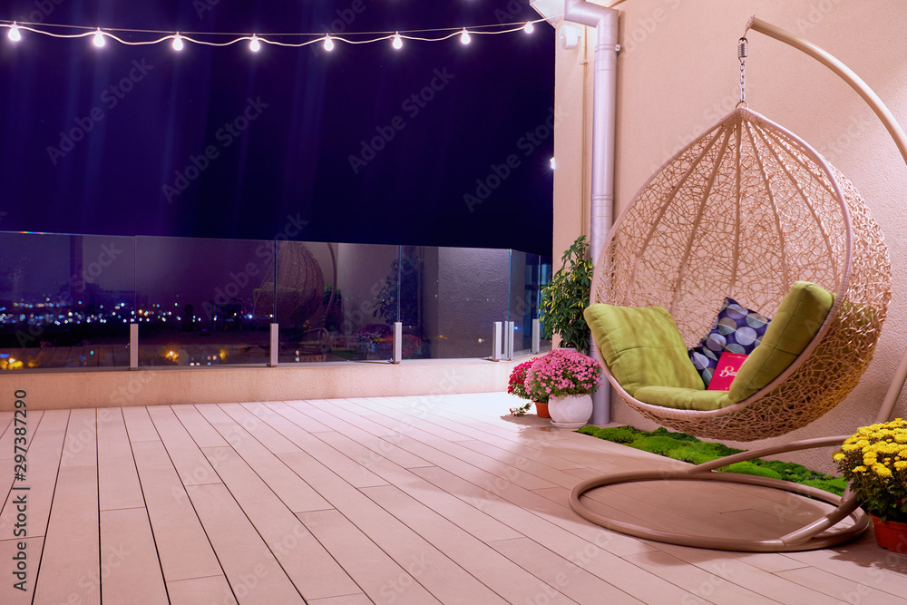 rooftop patio area with hanging swing chair and string lights at night - obrazy, fototapety, plakaty 