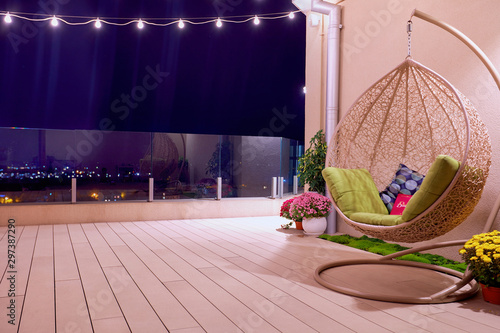 rooftop patio area with hanging swing chair and string lights at night