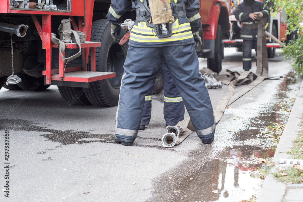 Fire brigade works on a machine with a hose. View from the back Fire brigade works on a machine with a hose. View from the back