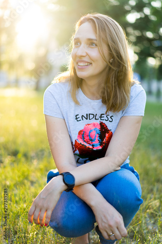 Portrait of a beautiful young modern woman with brown hair smiling and having fun outdoor in the summer, park with warm backlight at sunset