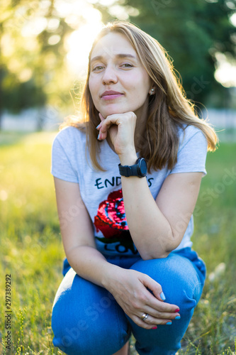 Portrait of a beautiful young modern woman with brown hair smiling and having fun outdoor in the summer, park with warm backlight at sunset