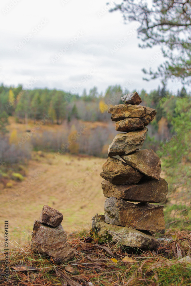 Stacked gray stones like a tower with an autumn forest in the background Stacked gray stones like a tower with an autumn forest in the background