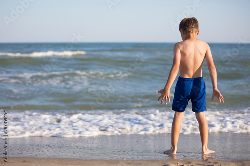 A boy near the sea is considering the waves. Child resting on the beach © Светлана Лазаренко