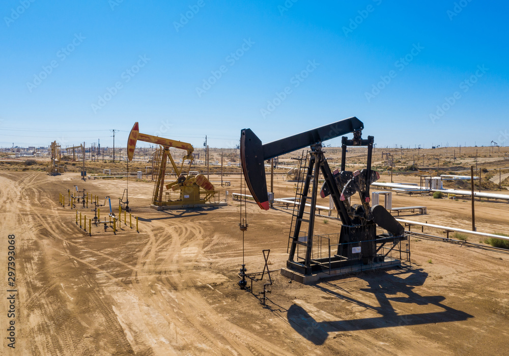 Black and yellow oil pumps. Pumpjack. Oil industry equipment. Rig energy machine for petroleum crude. Daylight, morning, blue sky. Aerial view. USA