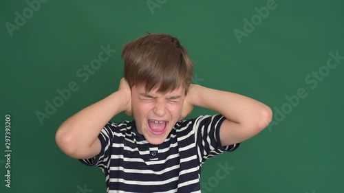 Young boy covering his ears with hands on the green screen photo