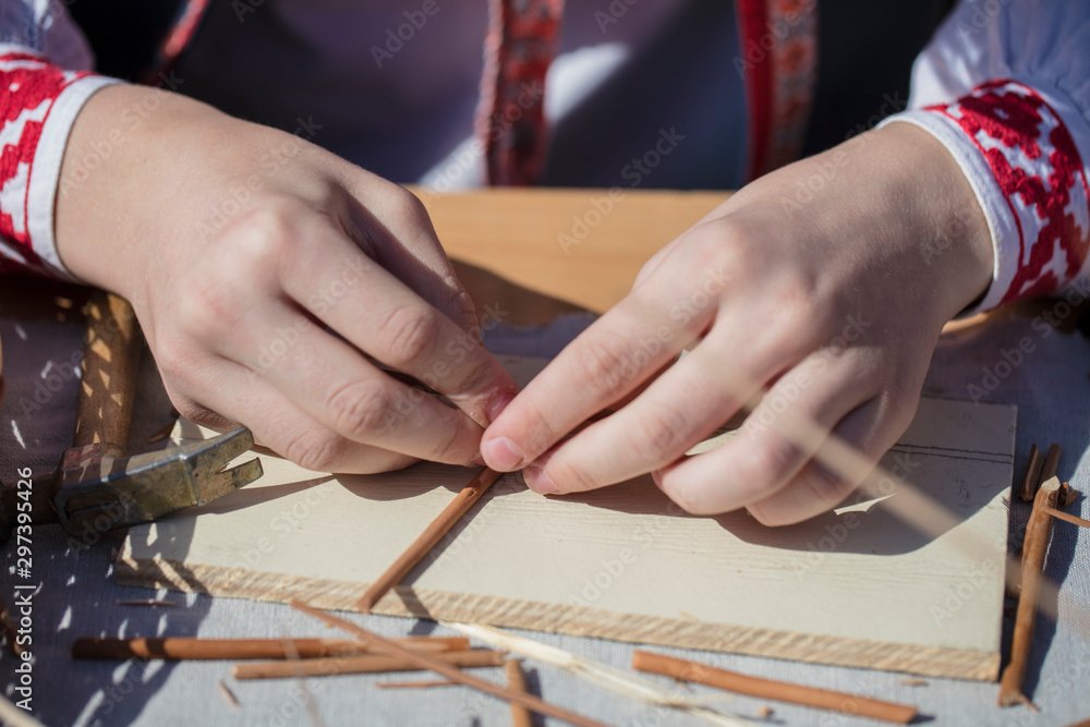 The hands of an artisan make a craft from straw. Hand made product