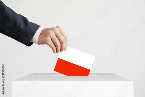 Election. Man putting a ballot with Polish flag into a voting box.