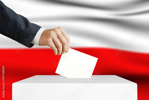 Election in Poland. Man putting a ballot into a voting box.