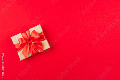 Cardboard gift box with bow on red background.