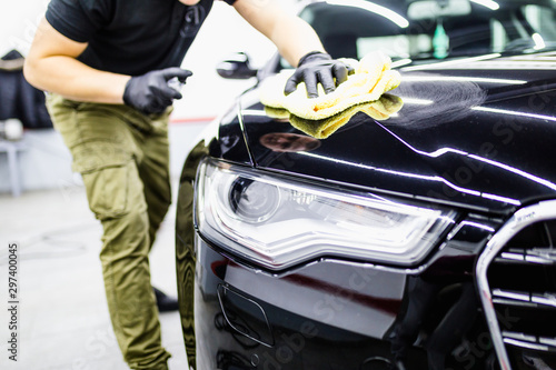 A man cleaning car with cloth, car detailing (or valeting) concept. Selective focus.