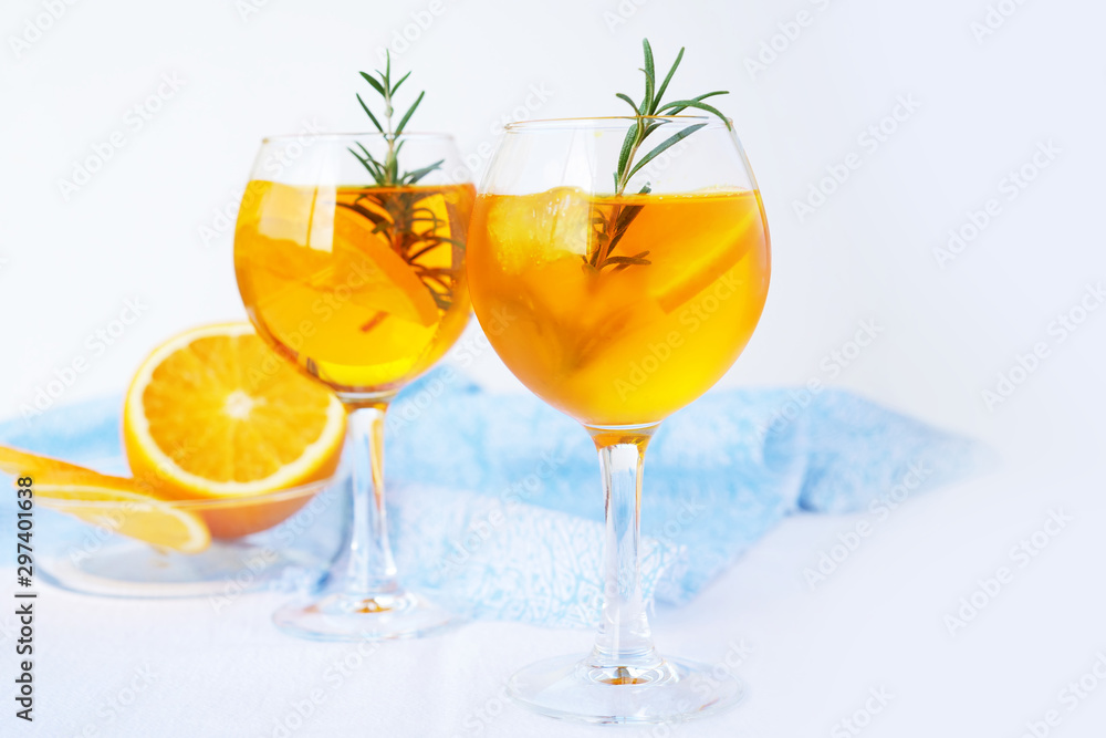 Refreshing cocktail with ice, oranges and rosemary in glasses over white background.