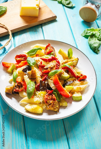 Pasta with grilled vegetables - zucchini, eggplant, pepper ant tomato on wooden background.