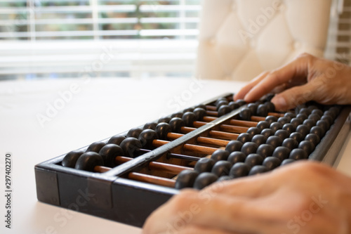 Young male hands holding old abacus performing addition, subtraction, division and multiplication.education mental math.count, add, subtract, multiply.Chinese math and history science.