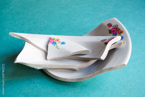 Pile of broken white plate on blue background. Concept of broken family or relations