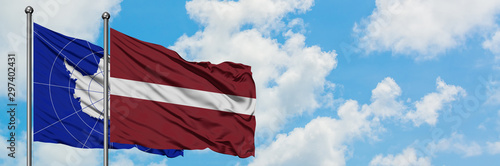 Antarctica and Latvia flag waving in the wind against white cloudy blue sky together. Diplomacy concept, international relations.