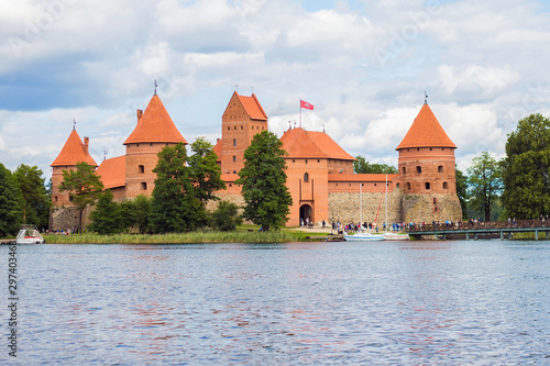 Yachts and medieval gothic Trakai Island Castle with stone walls and towers with red tiled roofs in lake Galve, Lithuania. Trakai Castle is one of major tourist attractions of Lithuania