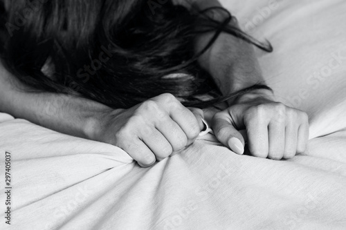 Woman's hands pulling white sheets in ecstasy, orgasm