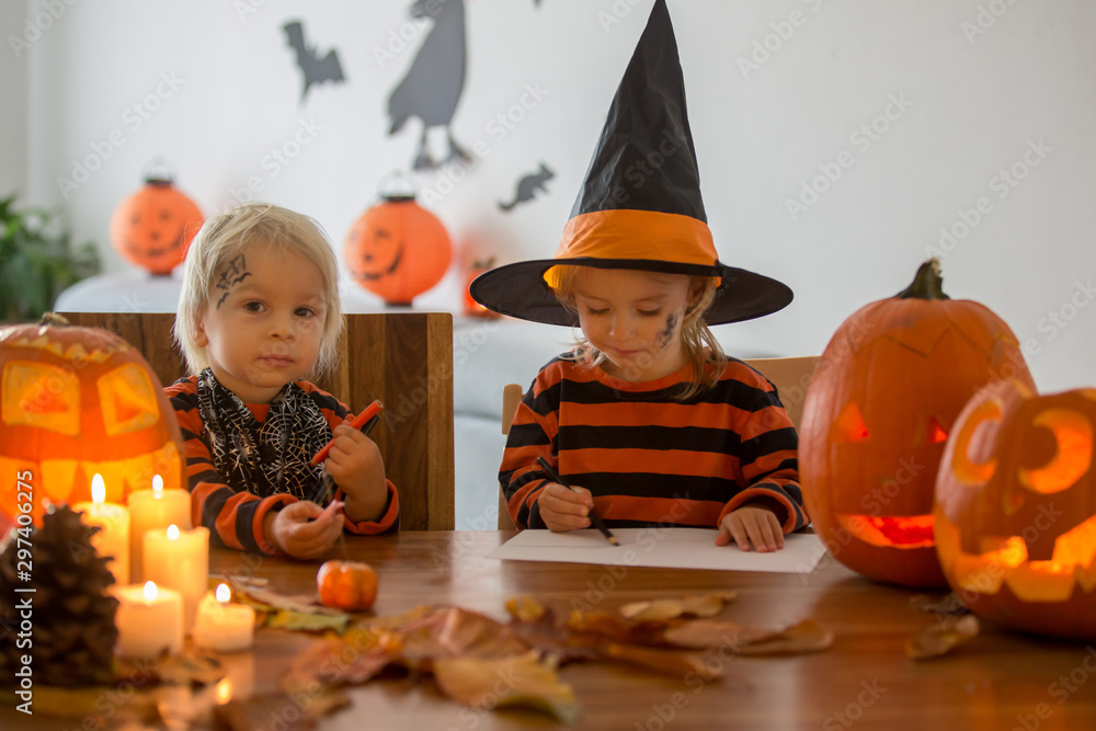 Fototapeta premium Adorable children, toddler boy and girl, drawing Halloween carved pumpking and playing with decoration