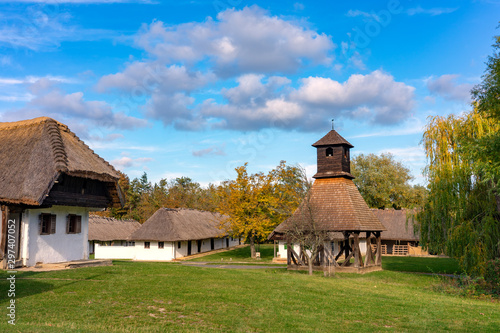 Historical old hungarian village with straw roof houses a bell tower