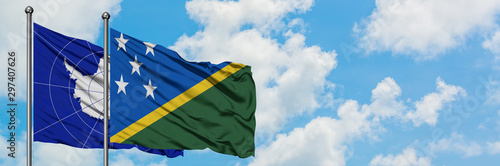 Antarctica and Solomon Islands flag waving in the wind against white cloudy blue sky together. Diplomacy concept, international relations.