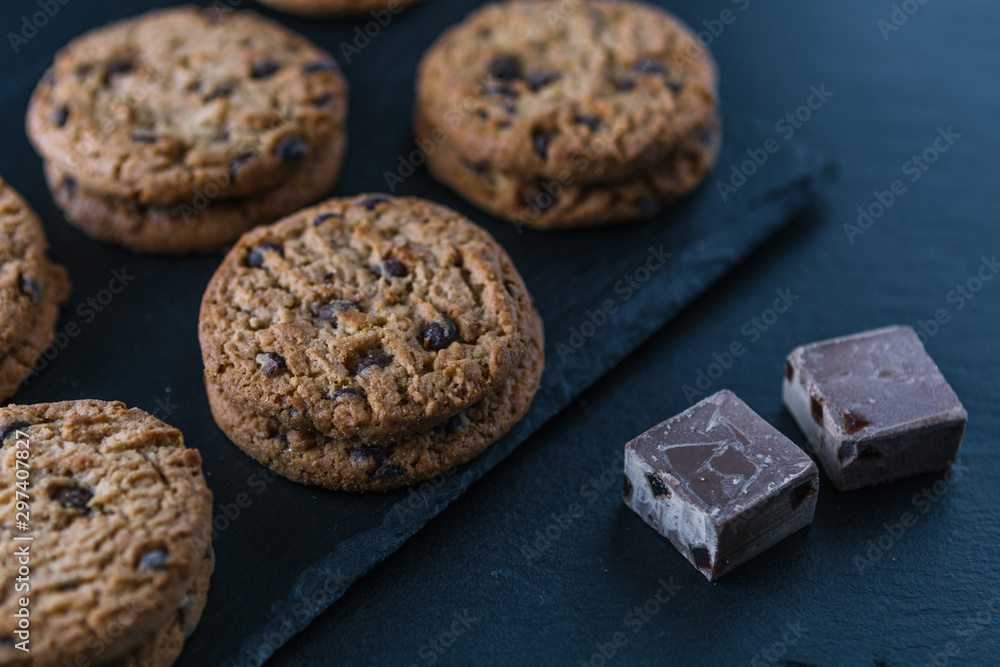 Fototapeta premium Handmade chocolate chip cookies and cocoa pieces on a chalkboard table.