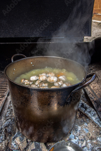 A pot of mushroom soup that is cooked over a fire in a mobile outdoor kitchen.