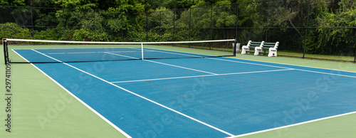 Sie view of blue tennis court with green boarder and benches to rest on © coachwood