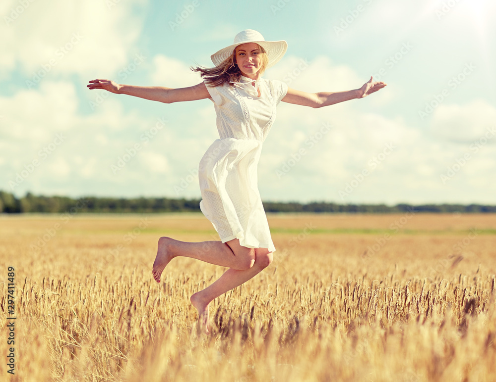 happiness, nature, summer, vacation and people concept - happy smiling young woman or teenage girl wearing straw hat and white dress jumping on cereal field happiness, nature, summer, vacation and people concept - happy smiling young woman or teenage girl wearing straw hat and white dress jumping on cereal field
