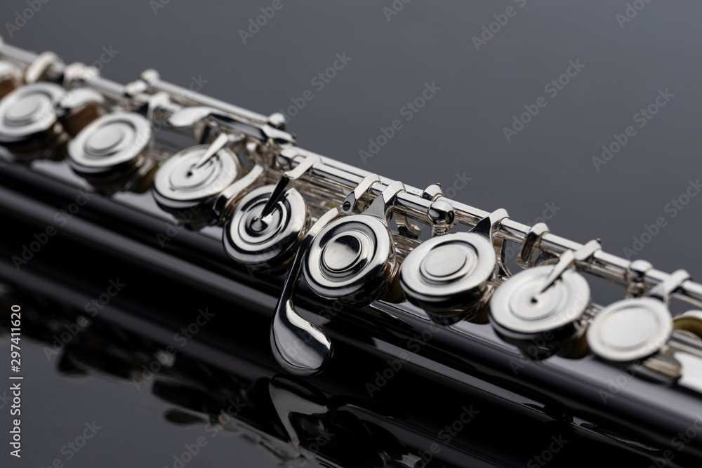 Naklejka premium A shiny silver plated flute on a reflective surface. An instrument common in a symphony orchestra