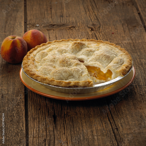 peach pie on a plate with two peaches 