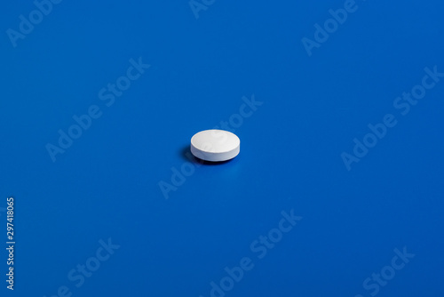 one white round pill on a blue background. Copy space for text.