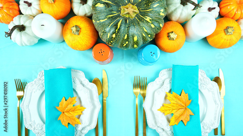 Happy Thanksgiving setting modern elegant blue orange and white themed table with pumpkins centerpiece overhead flat lay.