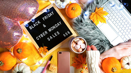 Preparation for Black Friday and Cyber Monday shopping hygge style Thanksgiving weekend concept with hot chocolate in bed with smartphone and laptop.
