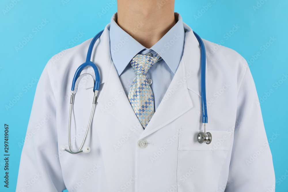 Doctor in medical gown with stethoscope against blue background, close up Doctor in medical gown with stethoscope against blue background, close up