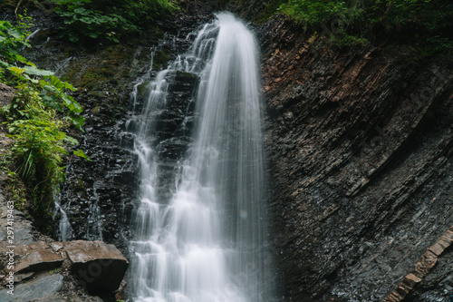 Beautiful waterfall in summer. A fast waterfall. View of the waterfall from below