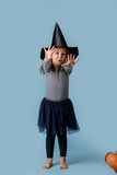 Girl in a witch costume pulls hands and shows fingers