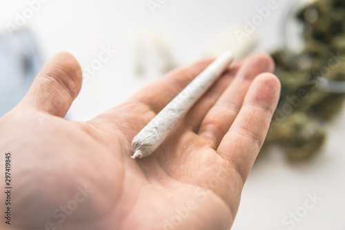 joint with marijuana weed on hand , close up, Cannabis buds on white table background, With light tinted