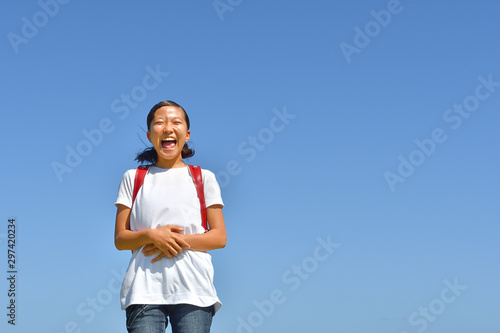 青空で笑う小学生の女の子（ランドセル） © hanapon1002