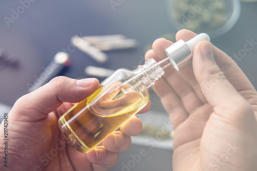 medical marijuana concept, hemp product, CBD cannabis OIL. Hand holding bottle of Cannabis oil in pipette, With light tinted