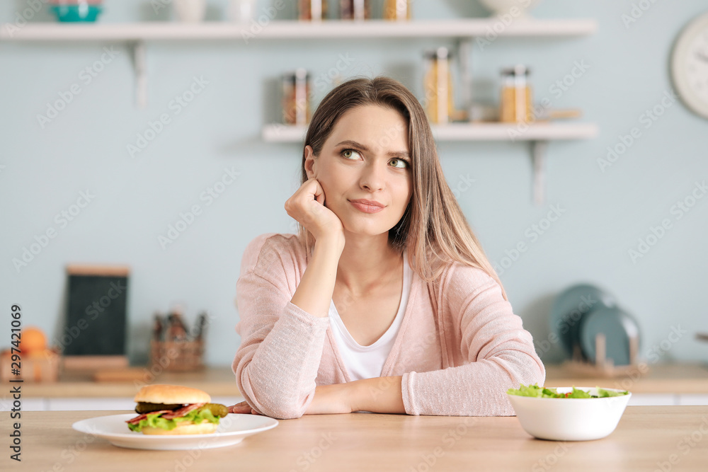 Woman choosing between healthy and unhealthy food in kitchen. Diet concept Woman choosing between healthy and unhealthy food in kitchen. Diet concept