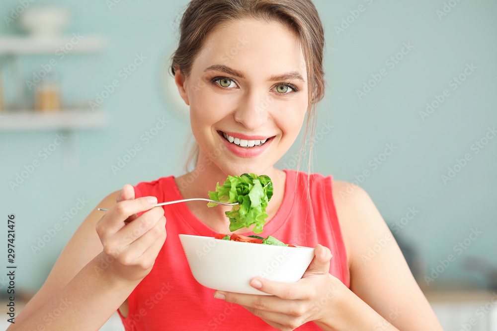 Young woman eating healthy vegetable salad in kitchen. Diet concept Young woman eating healthy vegetable salad in kitchen. Diet concept